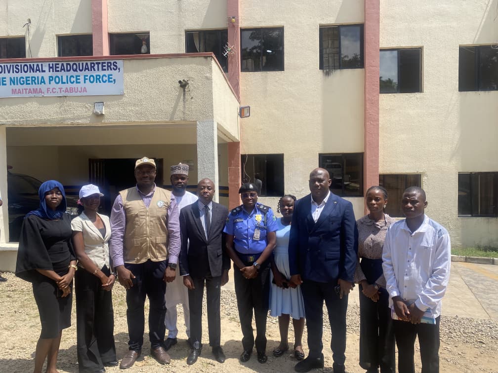 Oversight team with a police officer outside the Maitama Divisional Headquarters of the Nigeria Police Force, FCT Abuja
